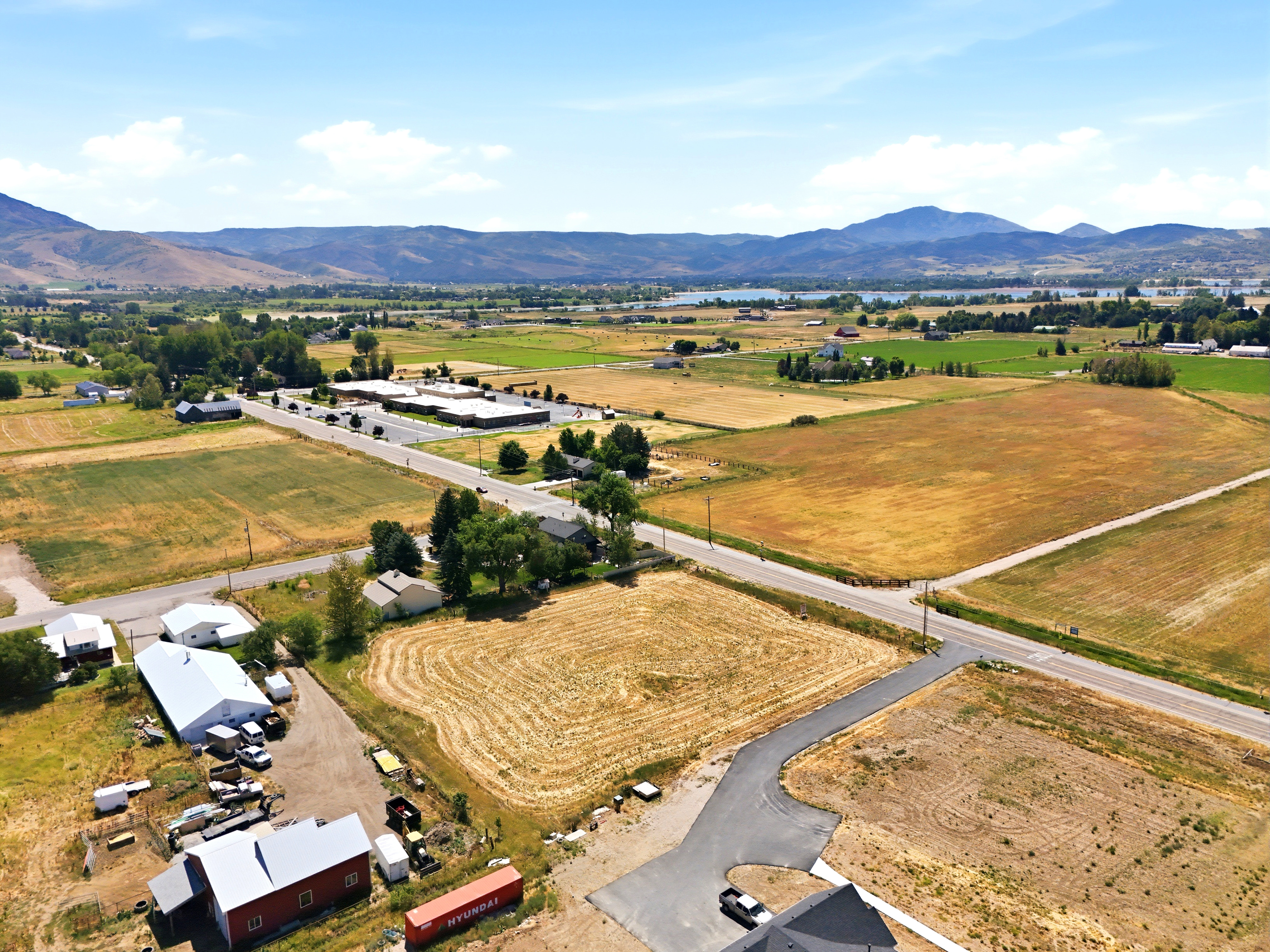 Expansive aerial capture showcasing diverse terrain with visible roads, agricultural fields, and a distant body of water