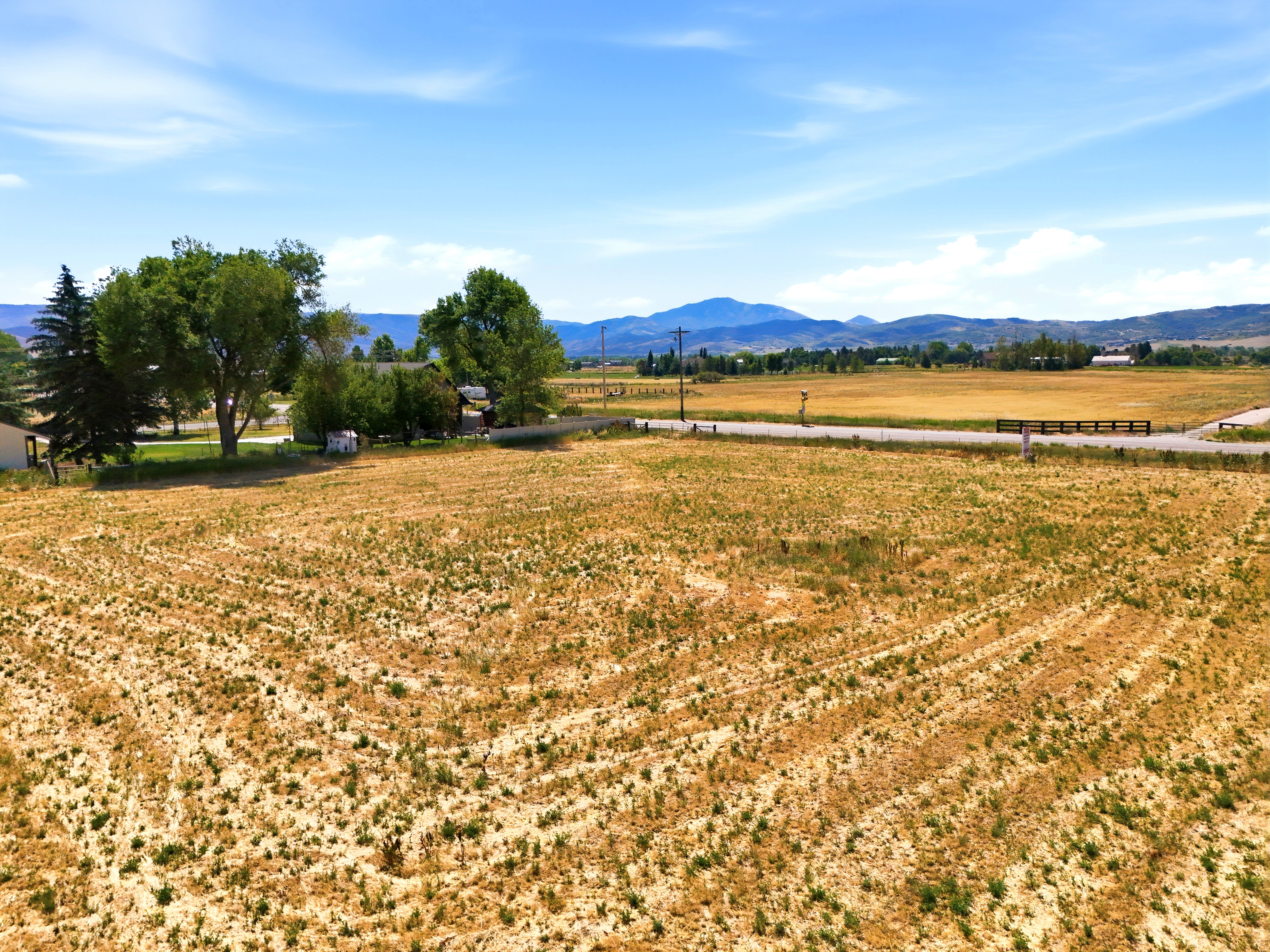 Expansive open land with distant mountain ranges and a partially visible residential structure