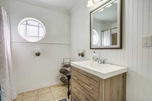 Full bath with vanity, ornamental molding, plenty of natural light, light tile patterned flooring, and a shower with curtain