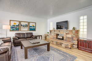 Living area with crown molding, a textured ceiling, wood finished floors, and a fireplace