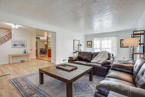 Living area with a textured ceiling, crown molding, and wood finished floors