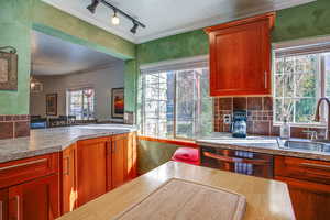 Kitchen with a textured ceiling, dishwasher, track lighting, crown molding, and light countertops
