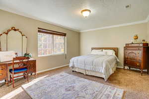 Bedroom with a textured ceiling, ornamental molding, and carpet flooring