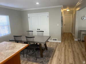 Dining area with crown molding and light wood finished floors