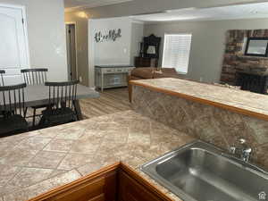 Kitchen featuring crown molding, tile counters, a fireplace, open floor plan, and a textured ceiling