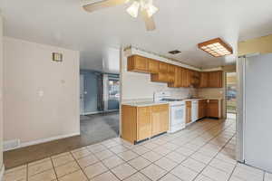 Kitchen with light countertops, white appliances, a ceiling fan, light tile patterned floors, and light colored carpet