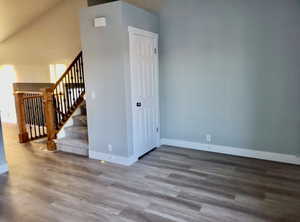 Unfurnished room featuring stairs and dark wood-style floors