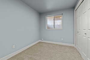 Unfurnished bedroom featuring a closet, carpet flooring, and a textured ceiling