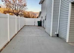 Patio terrace at dusk with a patio area, a fenced backyard, and a gate