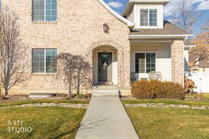 View of front of house with a shingled roof, a porch, and brick siding