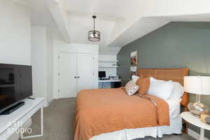 Carpeted bedroom featuring a closet, a desk, and lofted ceiling