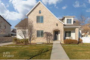 Traditional-style home with a shingled roof, a porch, and brick siding