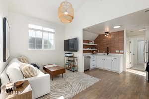 Living area with vaulted ceiling and light wood-style flooring