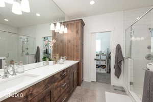 Bathroom featuring double vanity, a shower stall, light tile patterned floors, recessed lighting, and a spacious closet