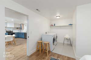Laundry area featuring washing machine and dryer, light wood-style flooring, and recessed lighting