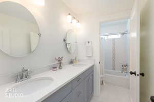 Full bath featuring double vanity, shower / bath combo, and light tile patterned floors