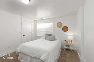 Bedroom featuring dark carpet, a textured ceiling, and a closet