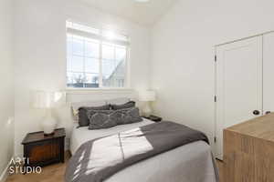 Bedroom featuring vaulted ceiling, wood finished floors, and a closet