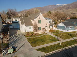 View of front of house featuring a mountain view, driveway, roof with shingles, and solar panels