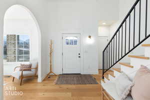 Entryway with light wood-type flooring, arched walkways, stairs, and a towering ceiling