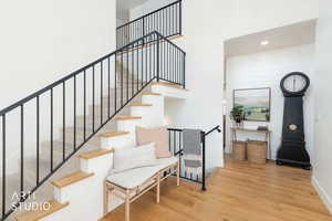 Stairway featuring wood finished floors, recessed lighting, and a towering ceiling