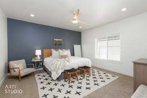 Bedroom with ceiling fan, light carpet, and an accent wall