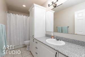 Full bath with vanity, light tile patterned floors, shower / tub combo with curtain, and recessed lighting