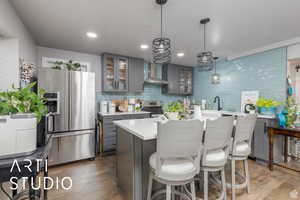Kitchen with a breakfast bar, decorative light fixtures, appliances with stainless steel finishes, gray cabinets, and a textured ceiling