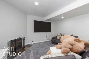Carpeted living area with a fireplace with flush hearth and recessed lighting