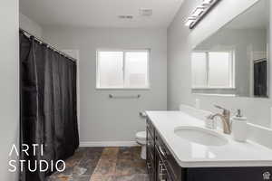 Bathroom featuring vanity, curtained shower, and stone finish flooring