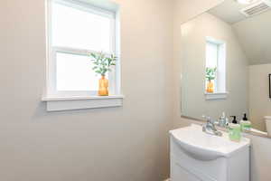 Bathroom with vanity and lofted ceiling