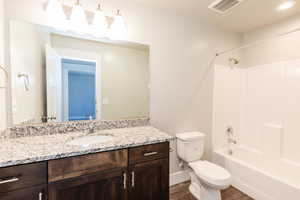 Full bathroom featuring vanity, shower / bath combination, and dark wood-type flooring