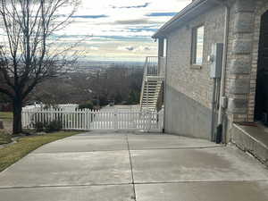 View of side of home with a gate, a patio, stairs, and brick siding