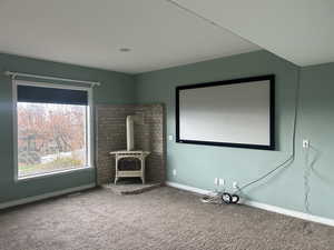 Home theater with a wood stove and carpet flooring