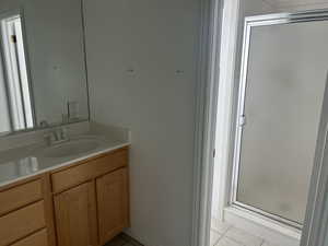 Bathroom with vanity, a stall shower, and light tile patterned floors