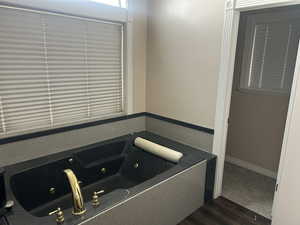 Bathroom with a whirlpool tub and dark wood-style flooring
