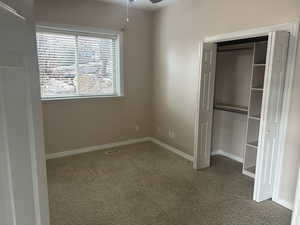 Unfurnished bedroom featuring light colored carpet, a closet, and ceiling fan