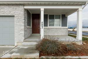 View of exterior entry with stone siding and covered porch