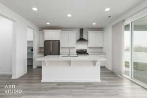 Kitchen with white cabinetry, light wood-style flooring, recessed lighting, wall chimney range hood, and stainless steel appliances