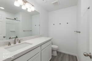 Bathroom featuring vanity, a shower, and dark wood-style floors