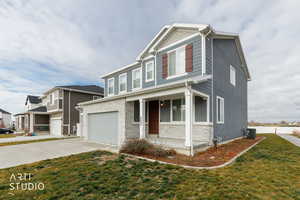 View of front of home with covered porch, driveway, a garage, and a front yard