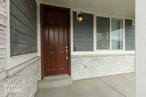 Entrance to property with a porch and brick siding