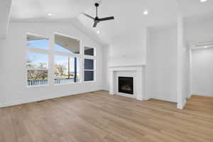 Unfurnished living room featuring light wood-style floors, a fireplace, a water view, ceiling fan, and recessed lighting