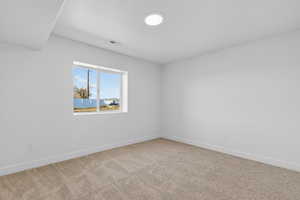 Spare room featuring light carpet and baseboards