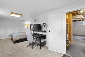 Bedroom with concrete block wall, secured water heater, and a desk