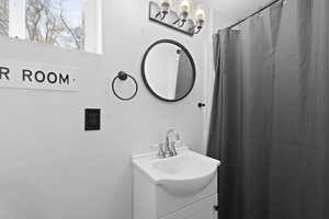 Full bath with curtained shower, vanity, and a chandelier
