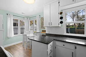 Kitchen featuring white cabinets, backsplash, freestanding refrigerator, and light wood-style floors