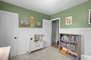 Game room featuring a wainscoted wall, a decorative wall, and light colored carpet