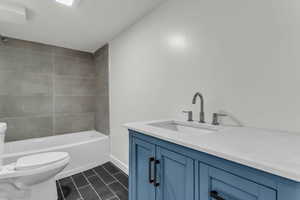 Full bathroom featuring vanity, shower / bathtub combination, and dark tile patterned flooring