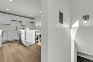 Kitchen featuring recessed lighting, white cabinetry, light countertops, light wood-style flooring, and dishwasher